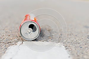 Aluminum can is flat lay,lying on a road. can fall on the street, It can be recycled.Summer day blurred background photo