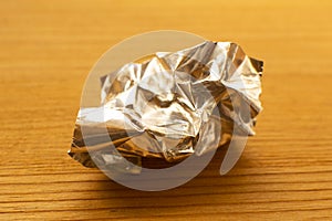 aluminum foil wrap without chocolate candy on a wooden background. Texture of used crumpled aluminium food foil.
