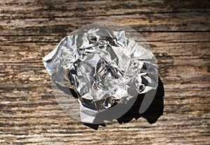 aluminum foil wrap without chocolate candy on a wooden background. Texture of used crumpled aluminium food foil.