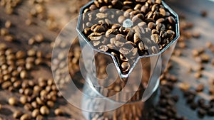 Aluminum geyser coffee maker close-up with scattered coffee beans on a wooden board