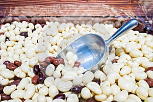 Aluminum scoop in a scattering of round white and brown dragees on a store counter. Delicious and healthy sweets made from nuts