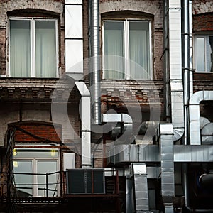 Aluminum ventilation pipes outside the old Industrial brick building of the factory, remade inside in a modern office