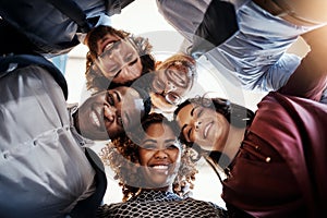 We alway put our heads together. Low angle portrait of a team of happy businesspeople putting their heads together in a