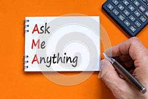 AMA ask me anything symbol. Concept words AMA ask me anything on white note on a beautiful orange background. Businessman hand.