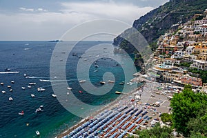 Amalfi Coast Positano Town panorama with low-rise buildings. Elevated view of many colourful umbrellas on a beach with leisure