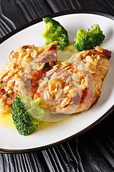 Amandine chicken with spicy almond sauce and broccoli close-up on a plate. vertical