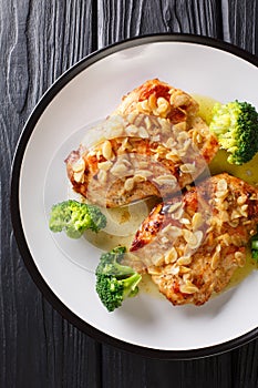 Amandine chicken with spicy almond sauce and broccoli close-up on a plate. Vertical top view