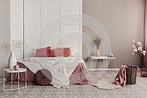 Amaranth pillow and orange bedding on king size bed in fashionable bedroom interior