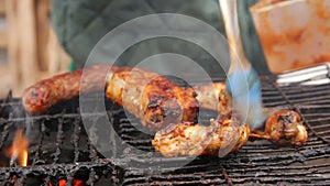 Amateur cook putting barbecue sauce on pieces of meat frying on dirty grill