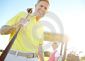 Amateur golfers. Low angle shot of a handsome older golfer standing in front of a golf cart with his golfing buddy