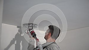Amateur man polishing home ceiling with sanding grinder machine