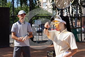 Amateur sports woman holding a racket while coach learning her how to play tennis. Professional assistant help tennis