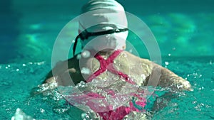 Amator female athlete doing butterfly stroke during training in indoor swimming pool, slow motion, full HD steady shot