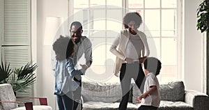 Amazed african american family dancing to music at home.