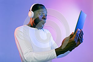 Amazed african american man using headphones and digital tablet