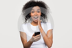 Amazed african girl user holding smartphone looking at camera