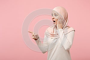 Amazed arabian muslim woman in hijab light clothes posing isolated on pink background. People religious Islam lifestyle