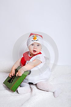 Amazed attractive baby girl in Christmas costume sitting and having fun