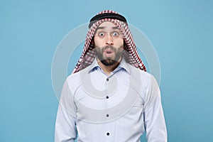 Amazed bearded young arabian muslim man in keffiyeh kafiya ring igal agal casual clothes  on pastel blue