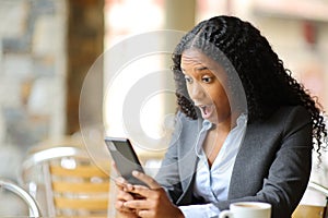 Amazed black executive checking phone in a bar