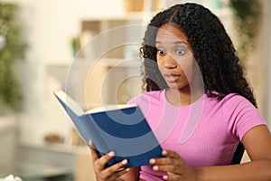 Amazed black woman reading a paper book photo
