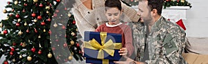 amazed boy opening christmas present near