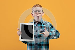 Amazed boy pointing at blank digital tablet screen