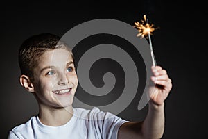 Amazed boy in white shirt holding sparkler