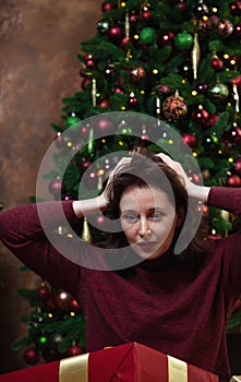 Amazed brunette woman on the background of the Christmas tree