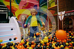 Amazed carefree preschool children playing together on indoor playground