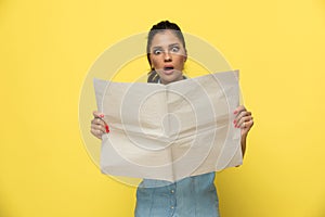 Amazed casual woman reading newspaper and gasping