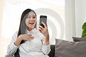 Amazed and cheerful Asian woman shocked with an unexpected news through her smartphone