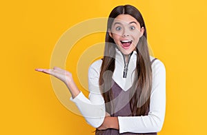 amazed child with long hair on yellow background. presenting product