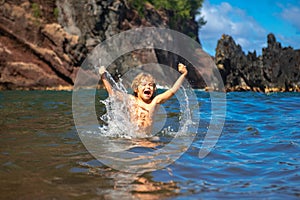Amazed child playing and splashing in the sea. Kid having fun outdoors. Summer vacation and healthy family lifestyle