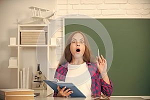 amazed child study at school with book on blackboard background, erudition