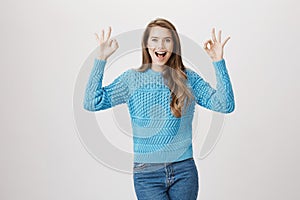 Amazed and excited attractive female blogger showing okay sign with both hands feeling great and expressing positive