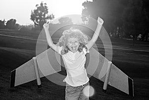 Amazed excited kid playing with toy plane on sunny golden sunset sky background outside on grassy summer hill. Dreaming