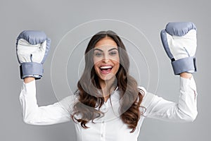 Amazed excited woman in boxing gloves. Successful businesswoman has boxing gloves while wearing a shirt isolated on gray