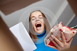 Amazed extremely happy woman looking inside box with grocery, making online shopping, holding package and consignment note in