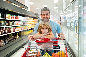 Amazed family father and child son with shopping cart buying food at grocery store or supermarket. Surprised face. Man