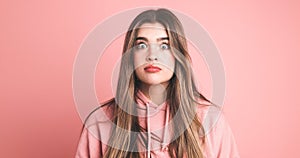 Amazed female model with wide open eyes over pink background