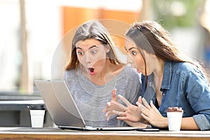 Amazed friends finding online content on laptop in a park