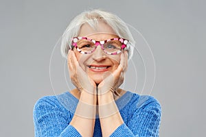 Amazed funny senior woman with big party glasses