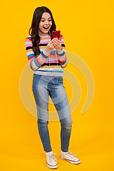 Amazed girl 12, 13, 14 years old with smart phone. Hipster teen girl types text message on cellphone, enjoys mobile app