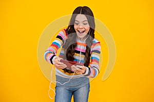 Amazed girl 12, 13, 14 years old with smart phone. Hipster teen girl types text message on cellphone, enjoys mobile app