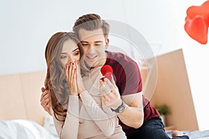 Amazed girlfriend looking at proposal ring held by boyfriend