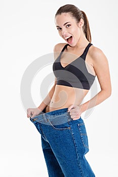 Amazed happy fitness woman became skinny and wearing old jeans