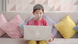 Amazed happy schoolboy raising arms and smiling while sitting on sofa celebrating victory in video game on laptop