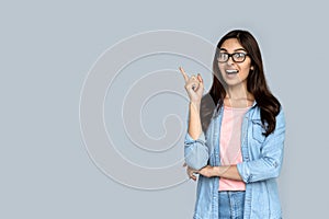Amazed indian girl pointing finger at copy space isolated on gray background