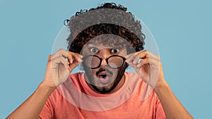 Amazed indian man removing eyeglasses and looking at camera